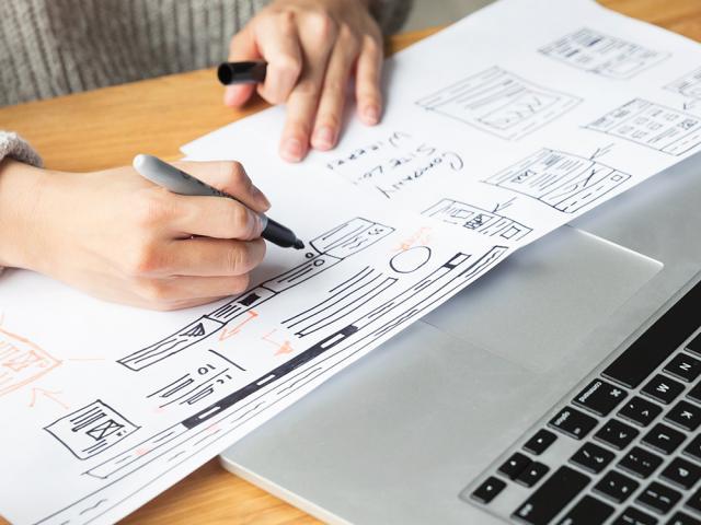 woman drawing a plan diagram in front of a laptop